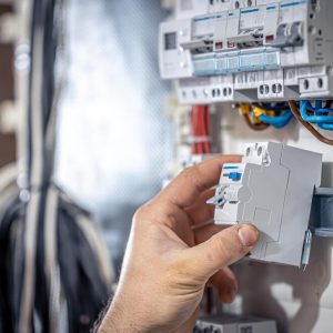 male-electrician-works-switchboard-with-electrical-connecting-cable_169016-16570